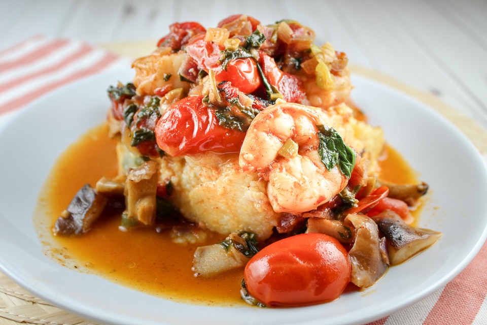 This Shrimp and Grits with Spinach & Tomatoes is a dish that will impress your friends and family! It is as delicious as it is beautiful! These cheesy grit cakes are smothered with jumbo shrimp, sauteed mushrooms, tomatoes and spinach. 