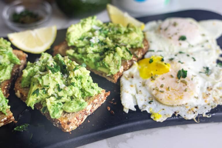 Copycat First Watch Avocado Toast made with thick-cut whole grain toast, smashed avocado, lemon, extra virgin olive oil and flaky sea salt, served with two basted eggs.