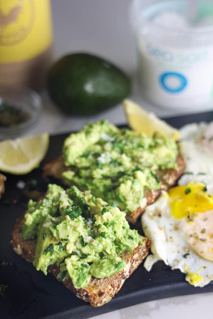 Copycat First Watch Avocado Toast made with thick-cut whole grain toast, smashed avocado, lemon, extra virgin olive oil and flaky sea salt, served with two basted eggs.