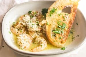 Copycat Carrabba's Shrimp Scampi in a rimmed dish with lemon butter sauce, parsley and Parmesan