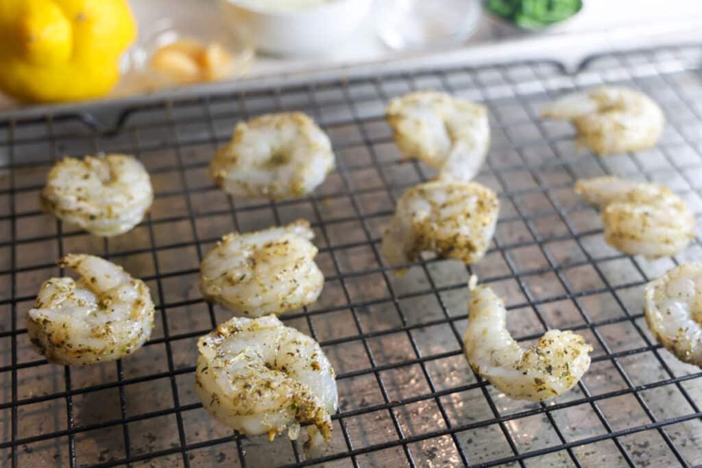 Raw shrimp tossed in olive oil and Italian seasoning on a baking sheet for copycat Carrabba’s Shrimp Scampi