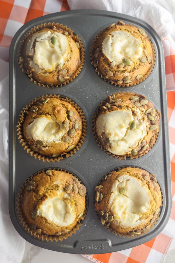 Starbucks pumpkin cream cheese muffins topped with cream cheese filling and chopped praline pumpkin seeds.